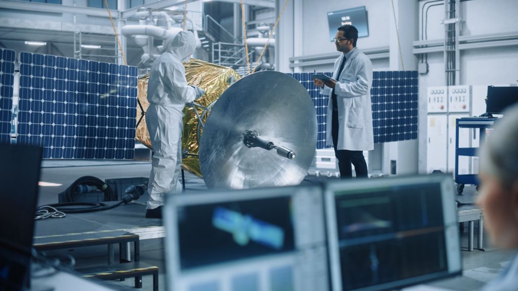 Managing Engineer and Chief Technician Working on Satellite Construction, Talk, Use Computer. Aerospace Agency Manufacturing Facility: Scientists Assemble Spacecraft for Space Exploration Mission